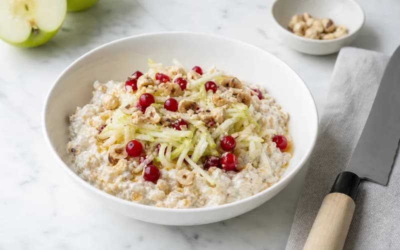 Bol de bircher muesli suisse avec pomme râpée, flocons d'avoine crémeux et noisettes concassées